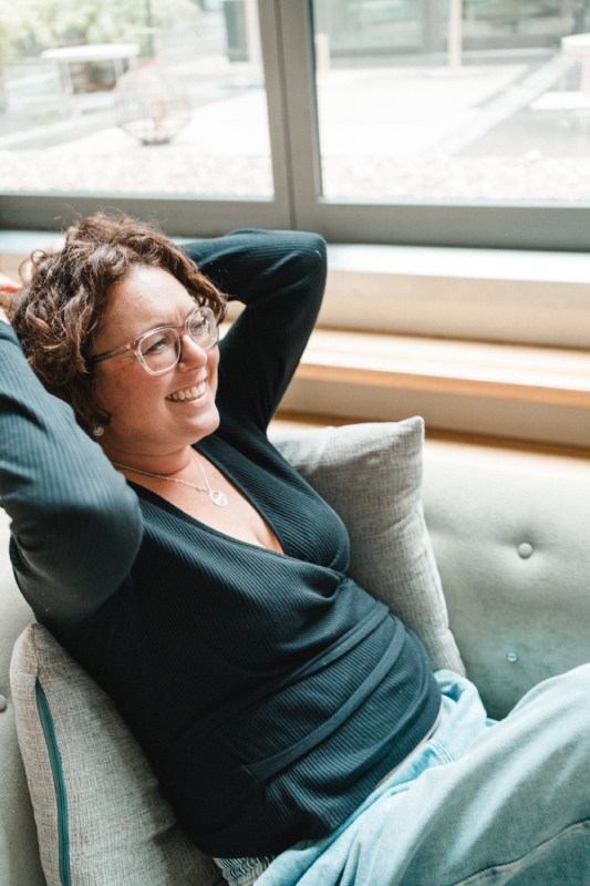 Fotografin lehnt sich entspannt in ein Sofa zurück.